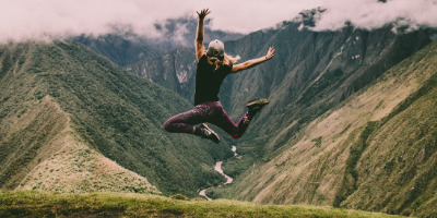 Fille sautant devant une montagne verte